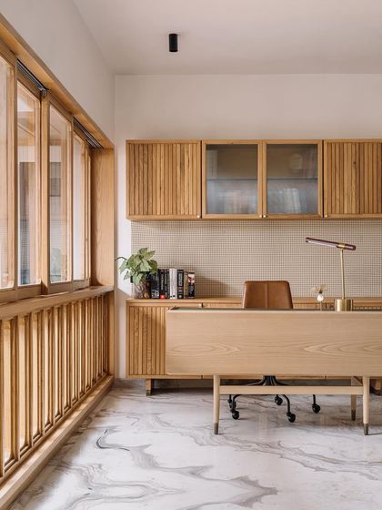This home office in Cocoon House is a study in texture and light. We used fluted wood for the cabinetry and a pegboard-style backsplash, creating a tactile and organized workspace. The large window with wooden mullions allows natural light to flood the room, making it a calm and inspiring place to work.