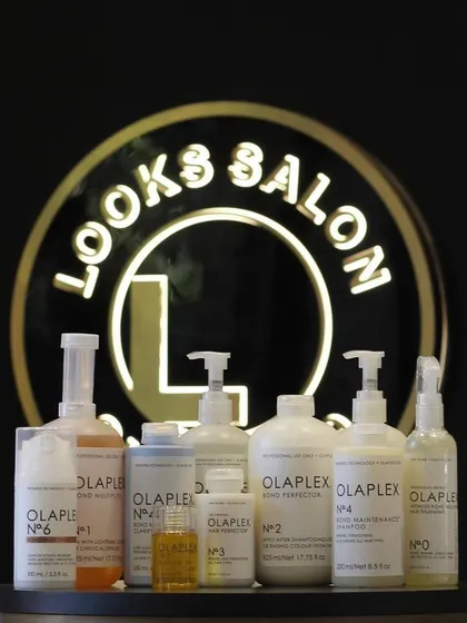 We use world-class products for all our services. This shot displays our full range of Olaplex bond-building treatments, set against our salon's emblem, signifying our commitment to quality and hair health.