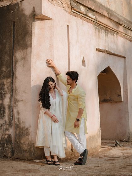 A shy, sweet moment shared against a rustic wall. This pre-wedding portrait of Vassundhara and Karan captures the simple, heartfelt beginnings of their journey.