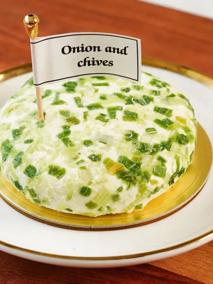 A hero shot of the onion and chives cheese spread, presented like a mini-cake with a flag, making it look special and artisanal.