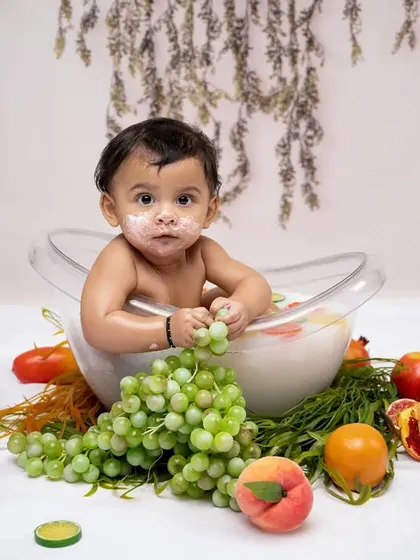 A fun and fruity milk bath session. This baby enjoys a tub full of milk and fresh fruit, creating a colorful and unique photoshoot experience.