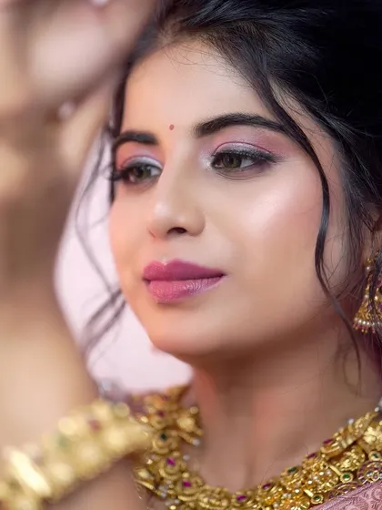 A detailed portrait shot focusing on the bride's glowing makeup and the exquisite craftsmanship of our temple choker and jhumka earrings.