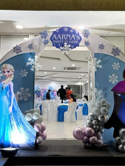 A magical entrance arch for a Frozen themed party, welcoming guests with life sized cutouts of Anna and Elsa.