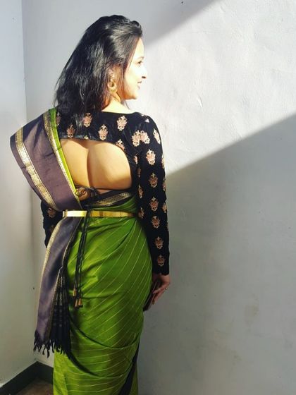 Our client looking radiant in a custom black full-sleeve blouse with a deep back, paired elegantly with a green Kanjeevaram saree.