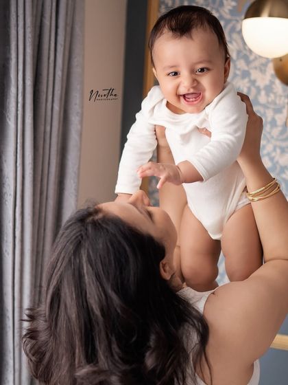 A mother lifting her smiling baby in the air.
