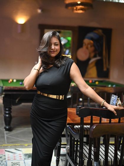 A sleek black dress for a party or evening event. This look is confident and stylish, perfect for hosting in a chic lounge or club setting.