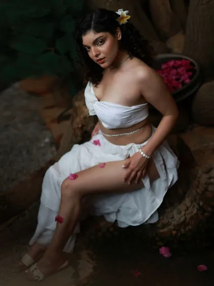 This shot from our Apsara series uses the rustic, earthy tones of the location to contrast with the pure white outfit. The high-angle perspective and scattered petals add to the artistic and dreamy quality of the image.