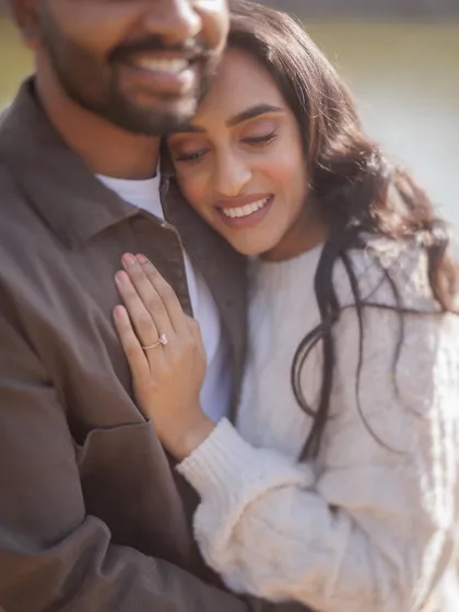 A close-up shot focusing on her serene expression as she rests her head on his chest. This image is all about quiet intimacy and trust, highlighting her beautiful engagement ring.