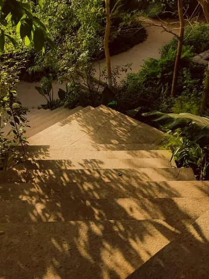 Dappled sunlight falls on the basalt stone staircase at Villa Toshi. This moment of pause captures the quiet beauty that emerges when architecture makes way for nature.