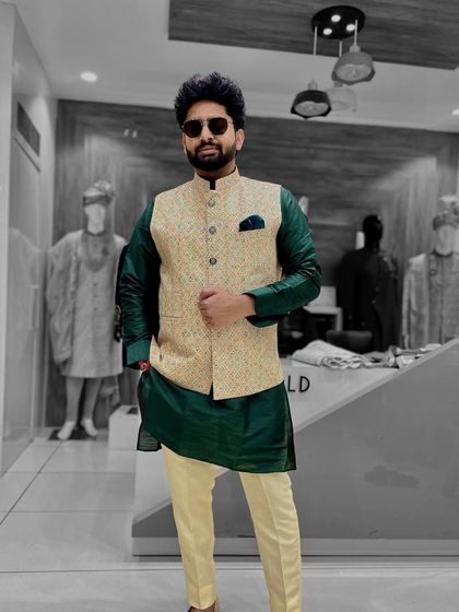 A client looking sharp in a dark green silk kurta paired with a cream-colored patterned Nehru jacket. The contrast between the two pieces creates a stylish and balanced look.
