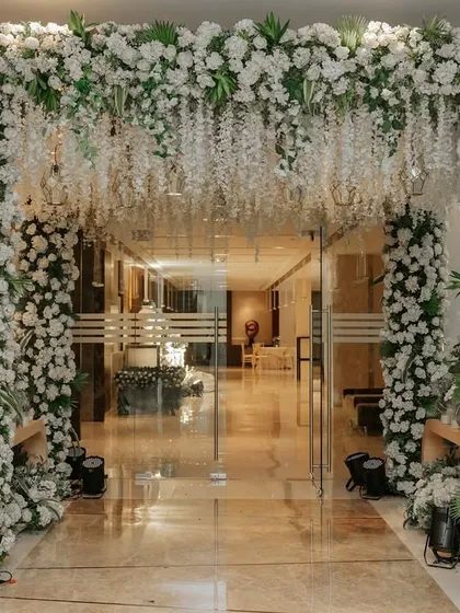 A breathtaking floral archway marks the entrance to this enchanted forest themed wedding. I used a dense arrangement of white flowers and greenery, with cascading wisteria, to create a lush and inviting portal into the celebration.