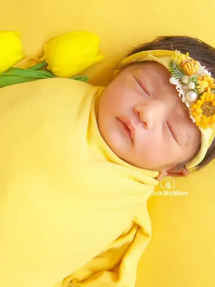 A bright and sunny close-up. The vibrant yellow of the swaddle and flowers beautifully highlights the baby's warm skin tone and peaceful sleep.