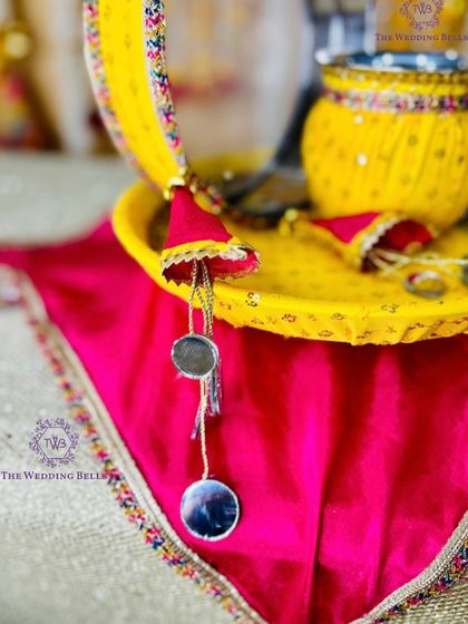 A detailed shot of our yellow and pink Karwachauth thali, highlighting the mirror-work hangings and vibrant, festive colors.