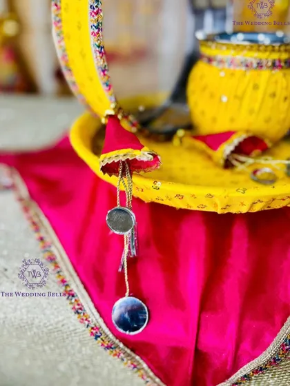 A detailed shot of our yellow and pink Karwachauth thali, highlighting the mirror-work hangings and vibrant, festive colors.