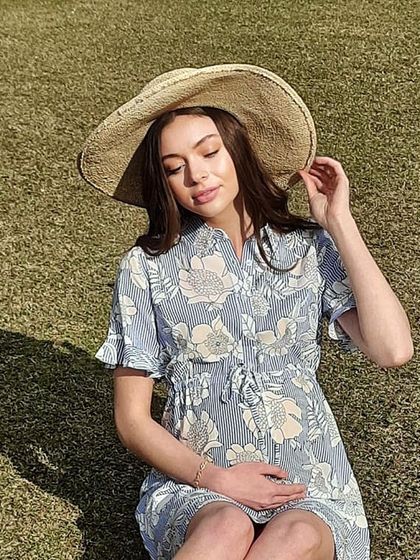 This shot from a maternity wear campaign features a relaxed and natural style. The makeup is minimal to enhance the model's healthy glow, and the hair is styled in soft, loose waves.