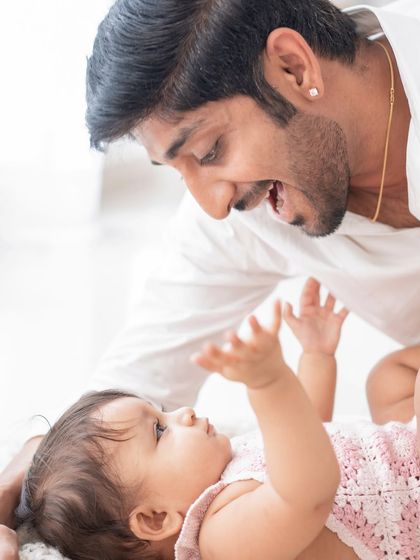 A father and baby sharing an interactive, playful moment on the floor.
