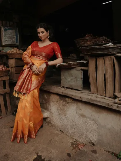 A relaxed yet elegant pose, with the model leaning against a wooden cart in the market, creating a beautiful contrast between her fine attire and the rustic setting.