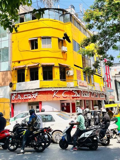 The real KC Das building on a busy day, with traffic and pedestrians creating a dynamic urban scene.