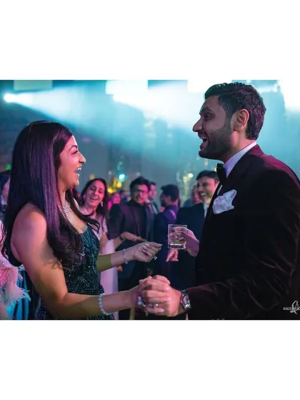 Tanya and Shivam lead each other through the party, holding hands in their unique way. This candid shot captures their connection and the lively atmosphere of the dance floor.