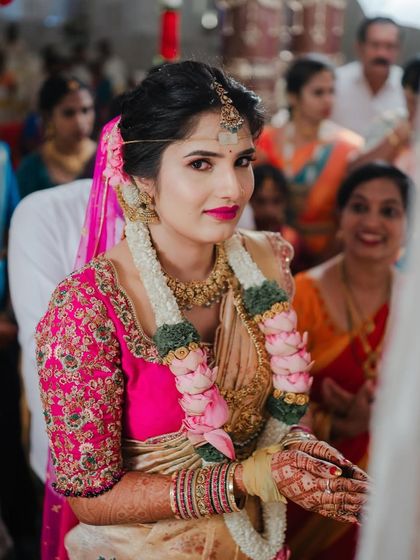 A bride during her wedding ceremony, her face full of emotion. Her cream and pink saree is a soft and elegant choice for the special day.