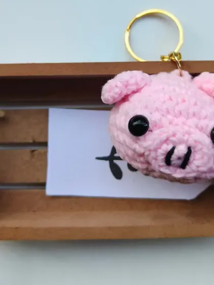 Another shot of the crochet piglet keychain, this time resting in a small wooden crate. I think the staging makes it look even cuter.