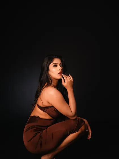 A low-key studio portrait where the model is crouched, creating a unique and powerful composition. The shadows and her intense gaze make this a very compelling shot.