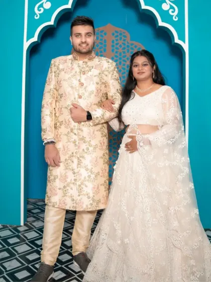 A regal couple's portrait. The intricate white lehenga and floral print sherwani create a perfectly coordinated look for a sophisticated pre-wedding shoot.