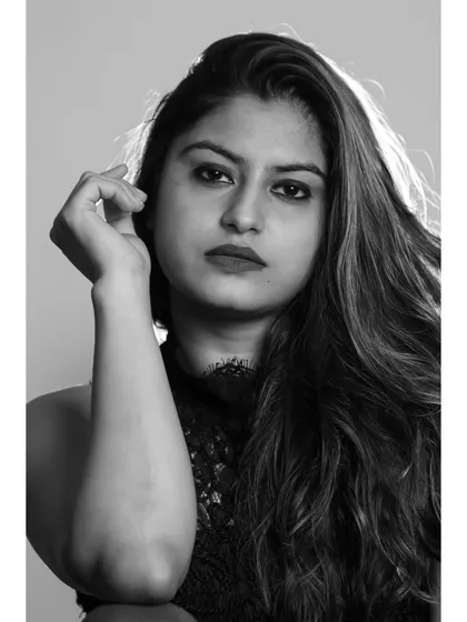 A close-up monochrome portrait with a direct, compelling gaze. The lighting highlights the texture of her hair and skin.