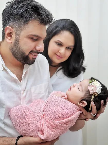 A beautiful pose showing both parents gazing lovingly at their newborn. The focus is entirely on the baby, highlighting how they have become the center of their parents' world.