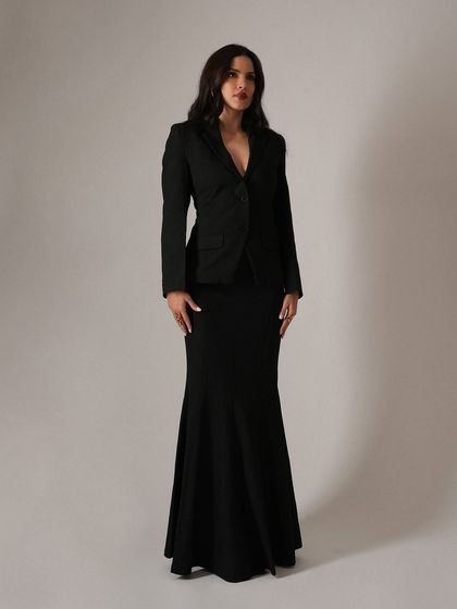 A clean, full-length shot that showcases the elegant and statuesque silhouette of the black blazer and mermaid skirt combination. This is a perfect example of timeless event styling.