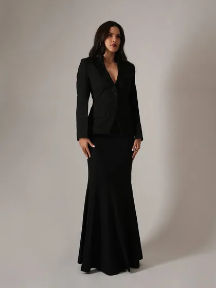 A clean, full-length shot that showcases the elegant and statuesque silhouette of the black blazer and mermaid skirt combination. This is a perfect example of timeless event styling.