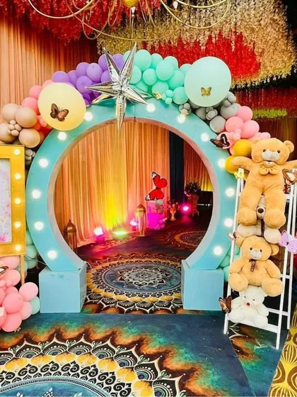 For a child's birthday, I bring their dreams to life. This butterfly-themed party entrance features a custom circular arch with lights, surrounded by colorful balloons and adorable teddy bears, creating a magical welcome for guests.