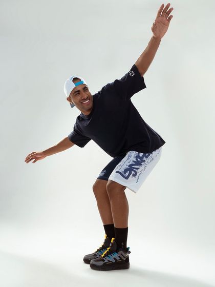 An action shot for a sportswear brand. The model's dynamic pose conveys energy and movement, perfectly capturing the athletic spirit of the apparel. The clean studio background keeps the focus on the subject.