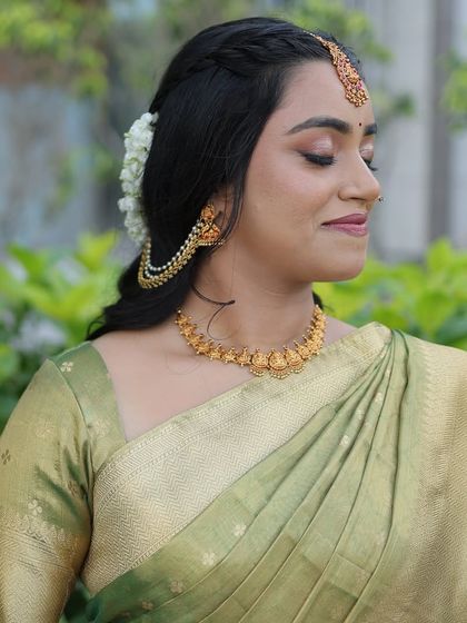 A side profile showing the beautiful hairstyle adorned with fresh jasmine. The makeup is kept soft and elegant to balance the traditional elements of the look.