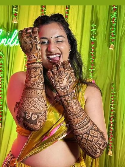 A fun and joyful photo of a bride winking and showing off her henna.