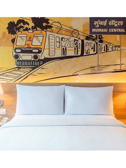This guest room at IBIS Vikhroli showcases a large mural of a Mumbai local train at Mumbai Central station, immersing guests in the city's energetic spirit through thoughtful hotel interior artwork.