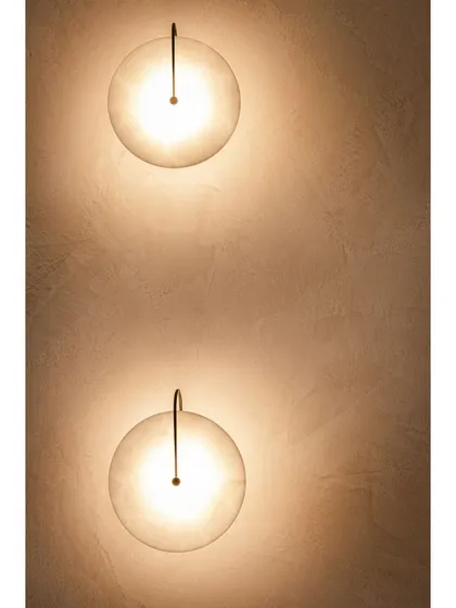 A detailed look at the wall lights, which feature a delicate hook and orb design, contributing to the modern Art Deco aesthetic.