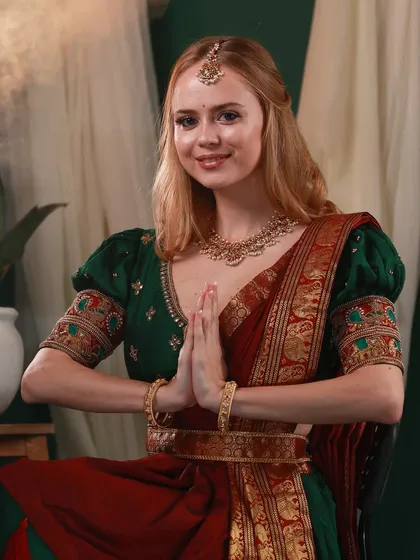 A respectful and elegant portrait of Irina Rudakova in a namaste pose, wearing a beautiful traditional South Indian lehenga.