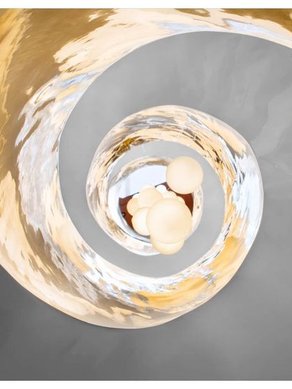 A view from the top of the Cleft House shows the spiraling light fixture, which mimics the form of the staircase below. This detail emphasizes the vertical axis of the home and adds a touch of artistic elegance to the rugged architectural shell.