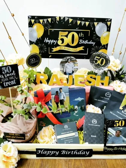 Celebrating a 50th birthday is a golden moment, and this hamper is designed to match. It features a sophisticated black and gold theme, a live plant, premium goodies, and personalized elements like a name display and photo memories.