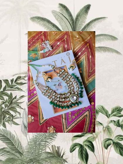 A detail shot of a bride's emerald and polki jewelry, laid out on a Taj-branded card.