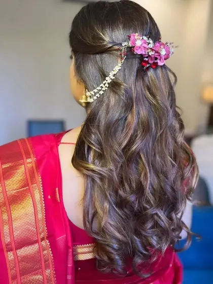 The back of the hairstyle, showing a beautiful floral accessory with pearl chains that adds a touch of modern elegance to the traditional look.