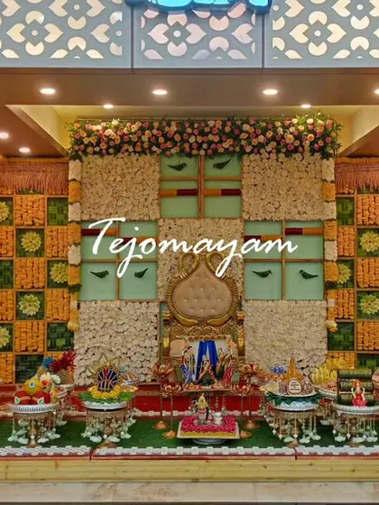 A baby shower setup with a unique checkered backdrop made of flowers and fabric. The two large golden pots add a touch of royalty.