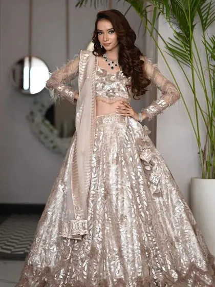 Two shots of a stunning silver and beige lehenga with feather-detailed sleeves. This is a sophisticated and modern choice for an engagement or reception look.
