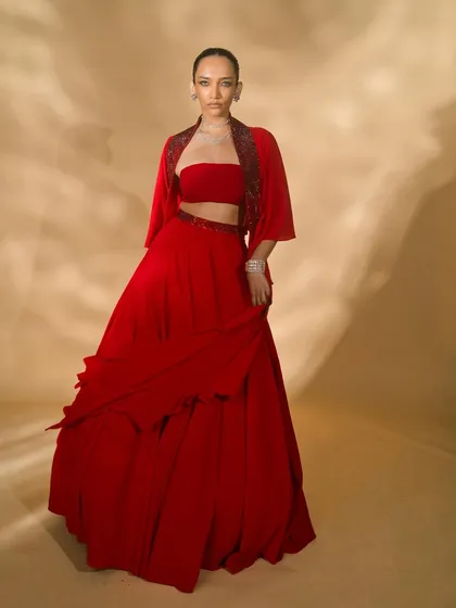 A look from the 'Scarlet Edit' featuring a red two-piece with a matching jacket. The model's pose is strong and confident, perfectly matching the bold aesthetic of the collection.