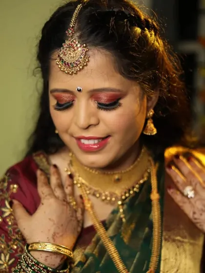 This bride's reception makeup features a stunning red and gold cut-crease eyeshadow. It's a bold and glamorous choice that pairs beautifully with her traditional gold jewellery.
