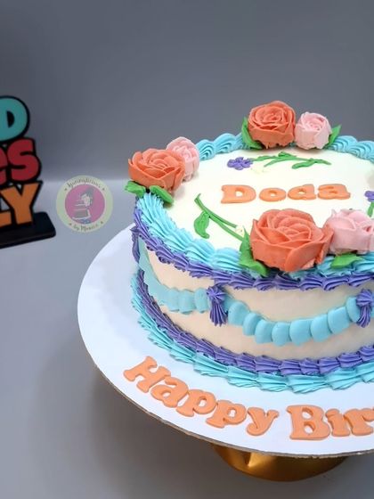 A colorful vintage-style cake with beautiful piped flowers in shades of orange, pink, and purple.