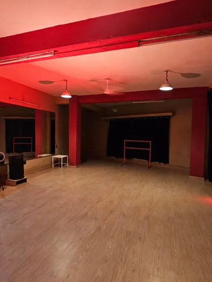 Another angle of the studio under a warm red light. You can see the clean, open layout and the professional blackout curtains that give you a blank canvas for any lighting setup.