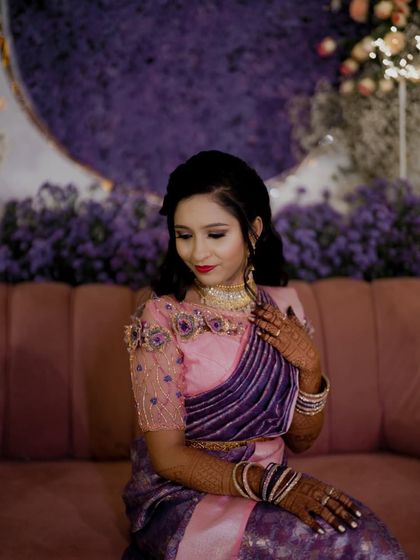 The bride looking serene and beautiful at her reception, seated against a backdrop of purple flowers.