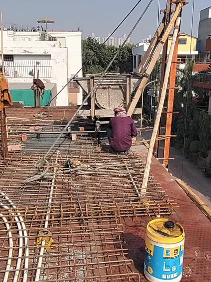 Workers engaged in the slab casting process, with electrical conduits being laid within the rebar mesh before the concrete is poured. This demonstrates the careful coordination required on-site to integrate structural and service-related elements seamlessly.